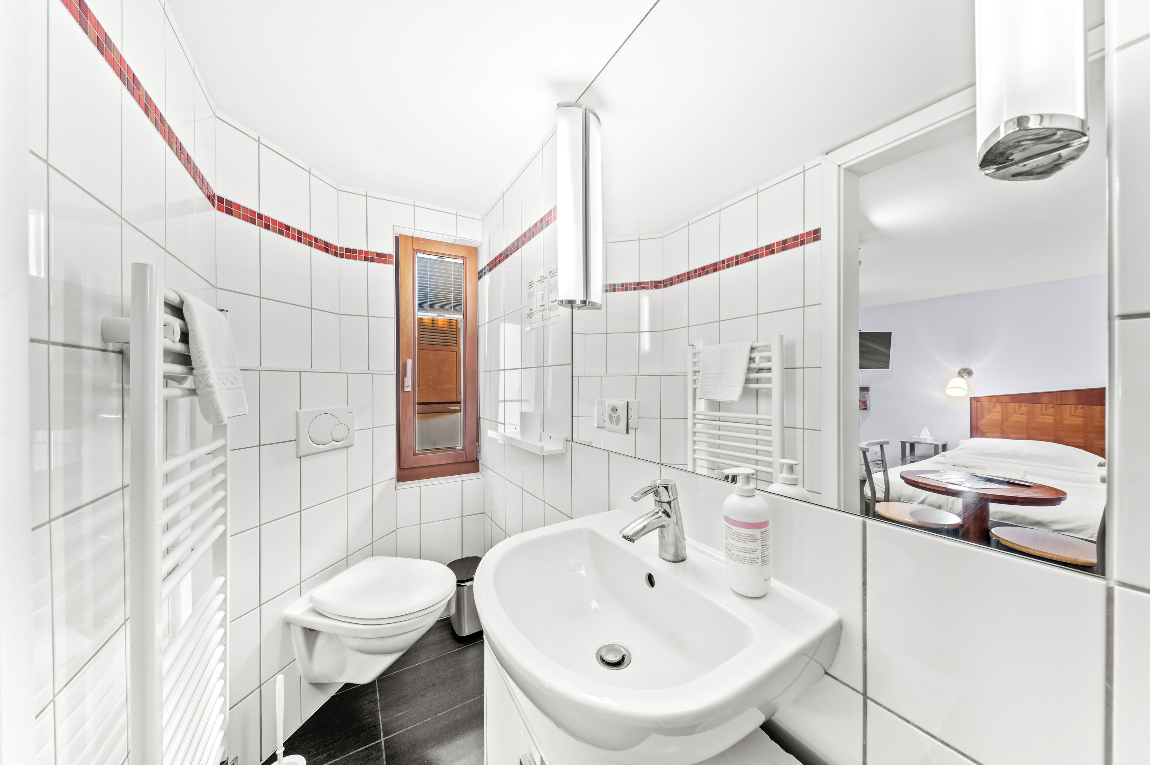 Een moderne badkamer met een witte wastafel, toilet en spiegel.