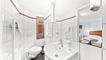 Een moderne badkamer met een witte wastafel, toilet en spiegel.