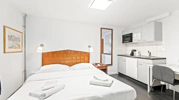 Une chambre d’hôtel comprenant un lit, un bureau, une kitchenette et une salle de bain.