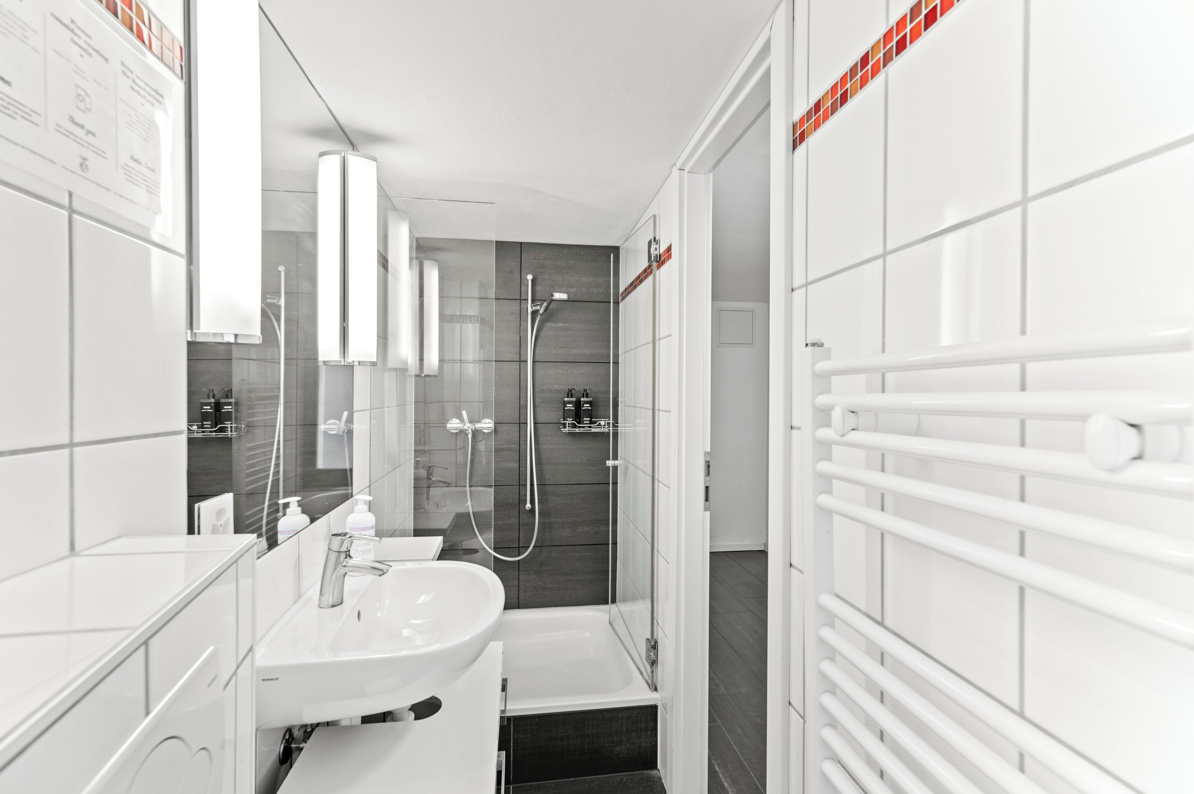 Une salle de bain moderne avec un lavabo blanc, un miroir et un espace douche.