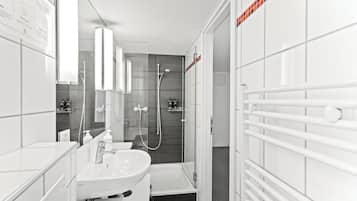 Une salle de bain moderne avec un lavabo blanc, un miroir et un espace douche.