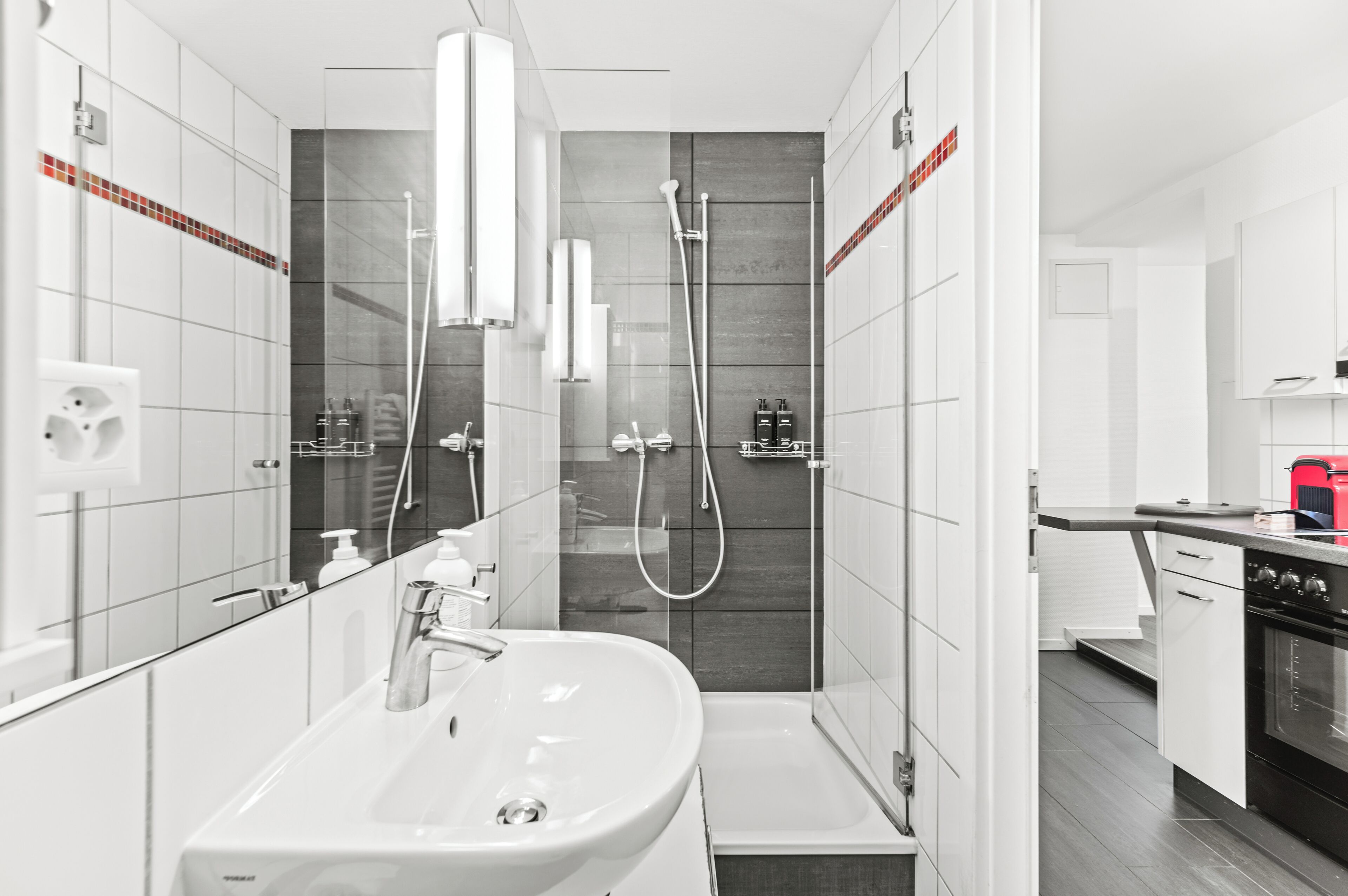 A modern bathroom with a large sink, mirror, and shower area.