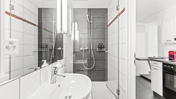 A modern bathroom with a large sink, mirror, and shower area.