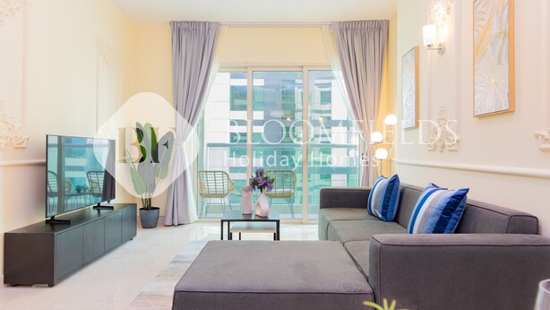 Ein modernes Wohnzimmer mit grauem Sofa, einem Flachbildfernseher, einem Couchtisch und einem Blumentopf.