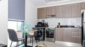 A modern kitchen with wooden cabinets, a built-in oven, and a dining area with a glass table and chairs.