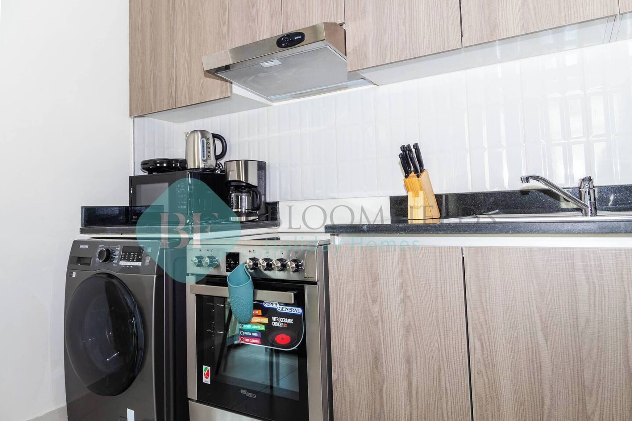 Une cuisine moderne équipée d’un lave-linge, d’une machine à café et d’un four.