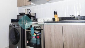 A modern kitchen with a washing machine, a coffee maker, and an oven.