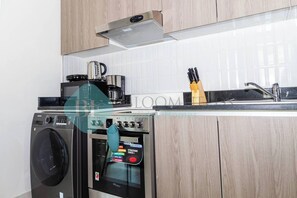 A modern kitchen with a washing machine, a coffee maker, and an oven.