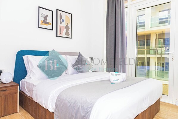 Une chambre à coucher comprenant un lit, une table de chevet, une commode et une fenêtre donnant sur un immeuble.