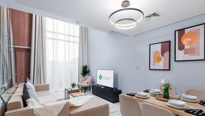 A modern living room with a sofa, coffee table, and dining area with plates and glasses. - Bloomfields Premium 1BR Duplex in Rukan (Dubai)