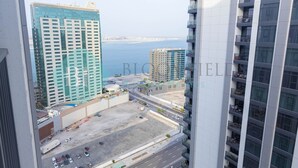 A high-rise hotel with multiple floors, a view of the sea, and a parking area. - Bloomfields Metropolitan 3BR In Bridges (Abu Dabi)