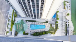 A modern building with a rooftop pool area, multiple balconies, and a landscaped garden. - Bloomfields Metropolitan 3BR In Bridges (Abu Dabi)