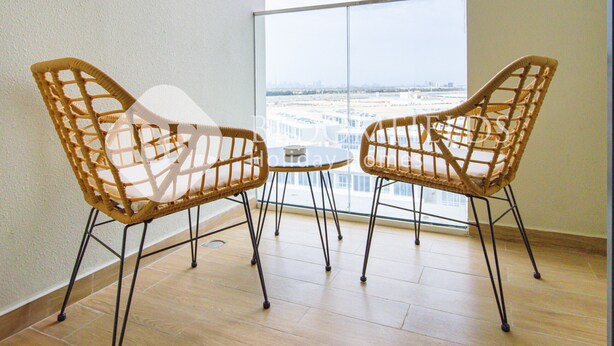 A balcony with two wicker chairs and a small table, overlooking a cityscape. - Bloomfields Stylish 2Br in Rukan (Dubai)