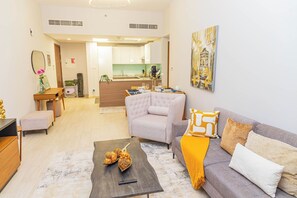 A modern living room with a sofa, coffee table, and ottoman. A kitchen is visible in the background. - Bloomfields Splendid 1BR in Al Jaddaf (Dubai)
