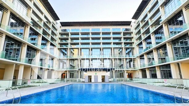 A modern building with a central swimming pool, multiple balconies, and a glass facade. - Bloomfields Iconic 1BR in Oasis Masdar (Abu Dabi)