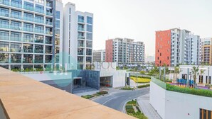 A modern hotel with a glass facade, multiple floors, and a landscaped area with pathways and greenery. - Bloomfields Cozy STU Azizi Riviera Meydan (Dubai)