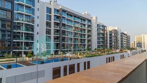 A modern residential building with multiple balconies, a rooftop pool, and a landscaped terrace. - Bloomfields Cozy STU Azizi Riviera Meydan (Dubai)