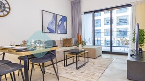 Una sala de estar moderna con comedor, ventanas grandes y vista a un edificio.