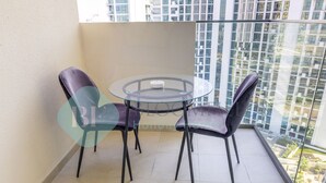 Un balc ón con una mesa de vidrio y dos sillas, con vistas a un paisaje urbano.