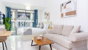 A modern living room with a sofa, coffee table, and a view of a balcony. - Bloomfields Pretty STU in Oasis (Abu Dabi)
