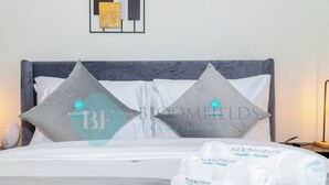 A neatly made bed with two pillows, a bedside table with a lamp, and a framed artwork on the wall. - Bloomfields Stunning STU in Reflection Al Reem (Abu Dabi)