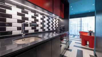 A modern kitchen with a black and white checkered backsplash, red cabinets, and a stainless steel sink.