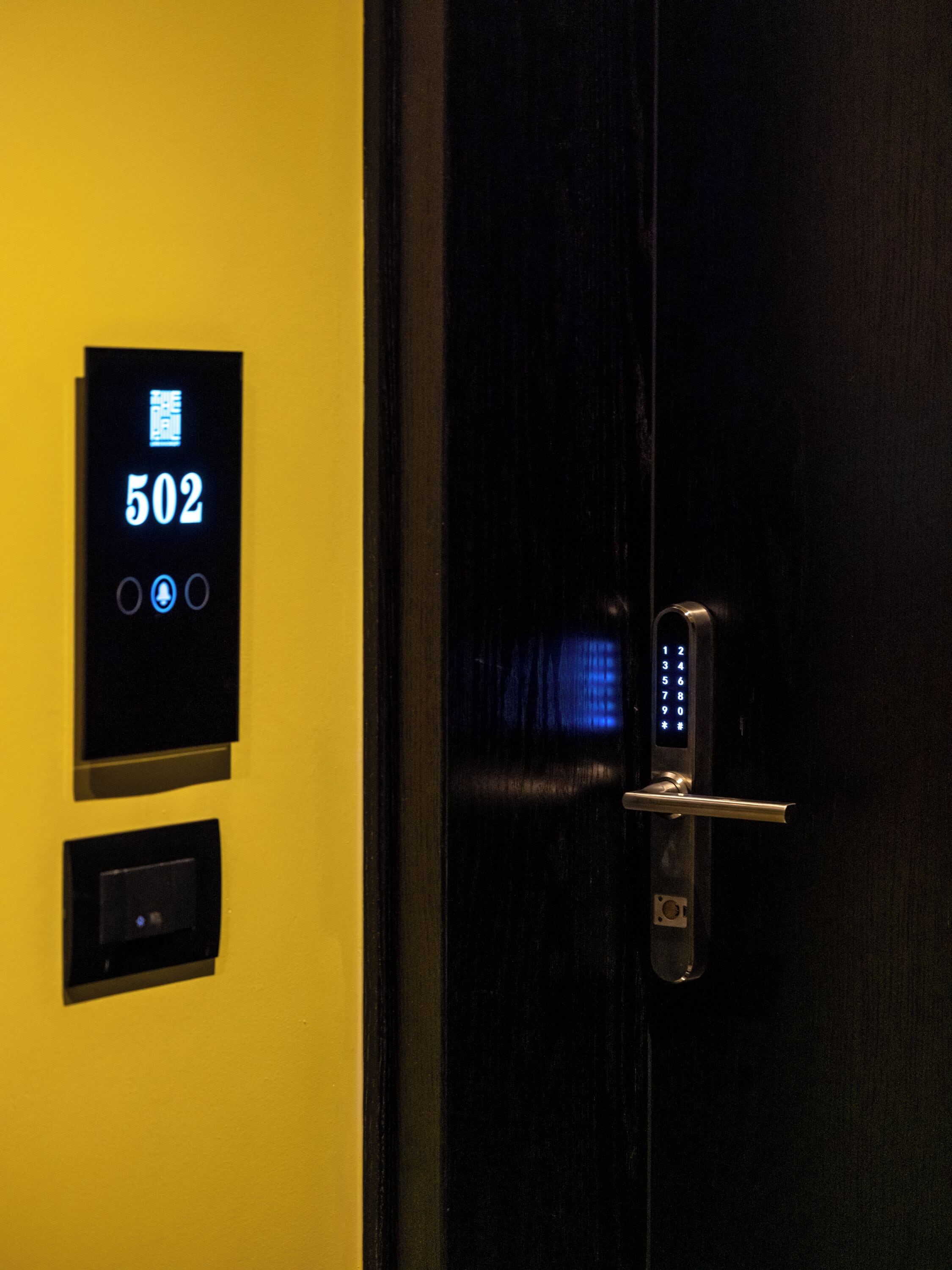 Une serrure à clavier numérique sur une porte, avec un écran affichant le numéro « 502 ».