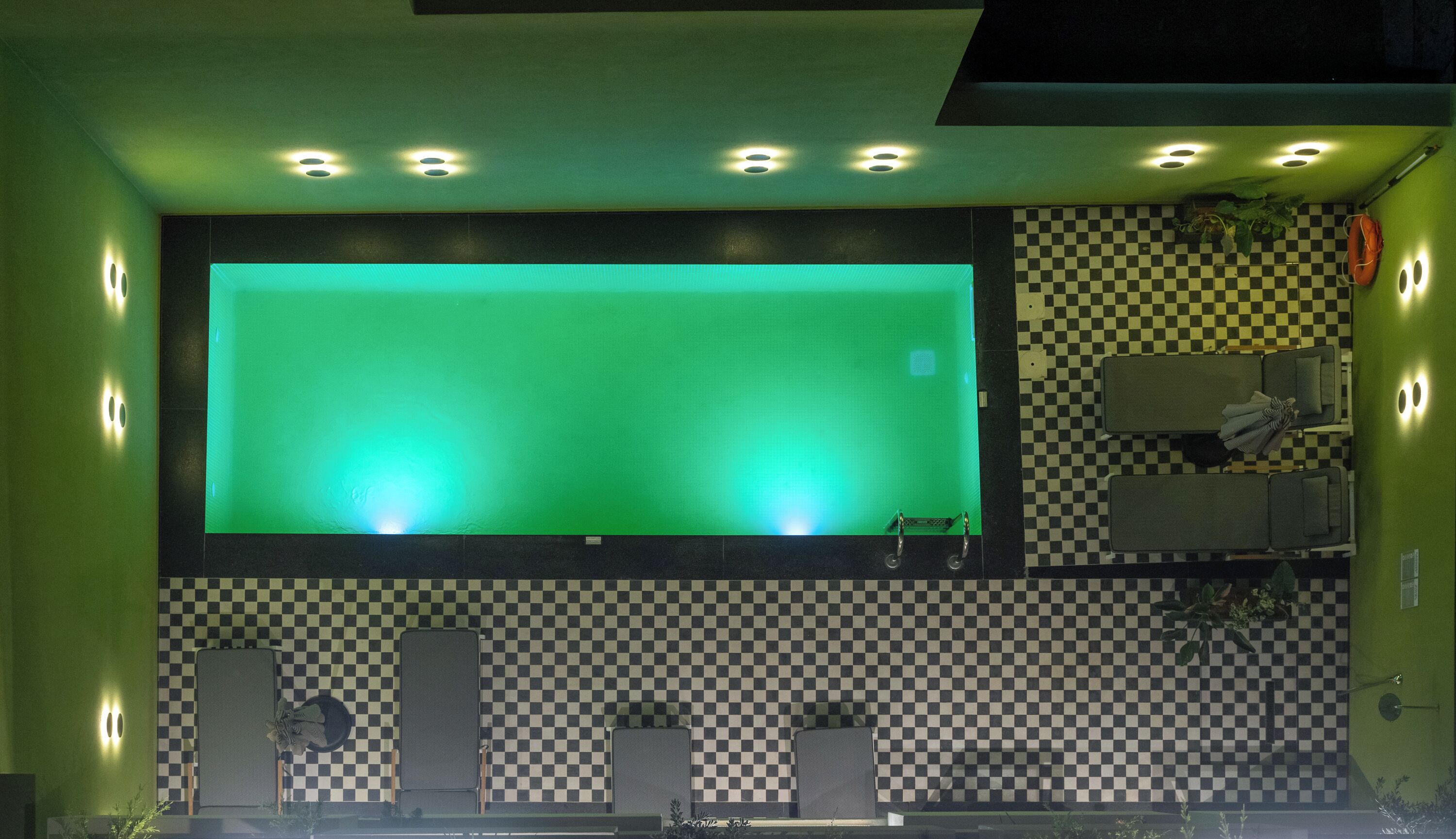 A room with a large green screen, checkered walls, and a ceiling with multiple lights.