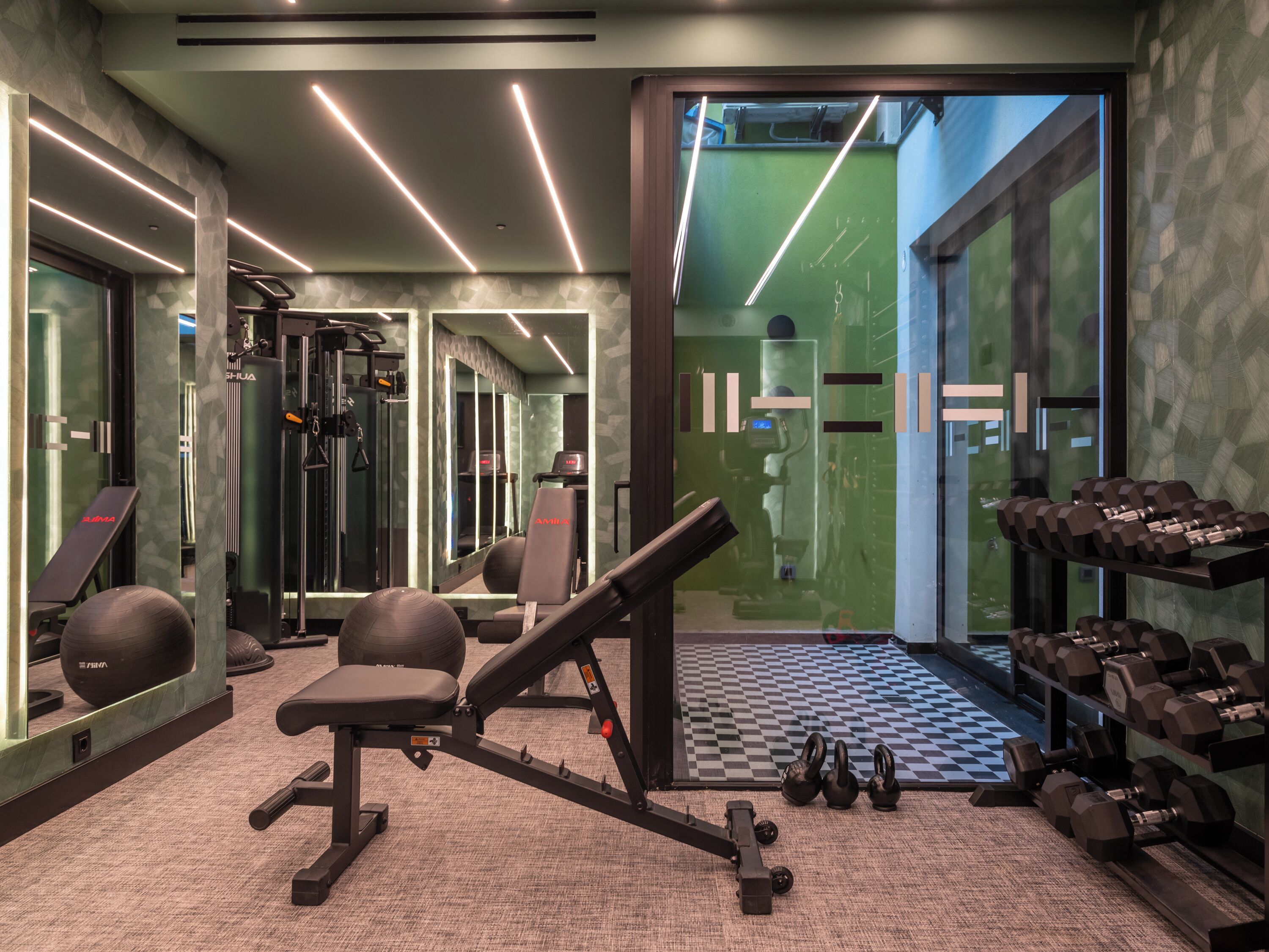 A gym with exercise equipment, a mirror, and a checkered floor.