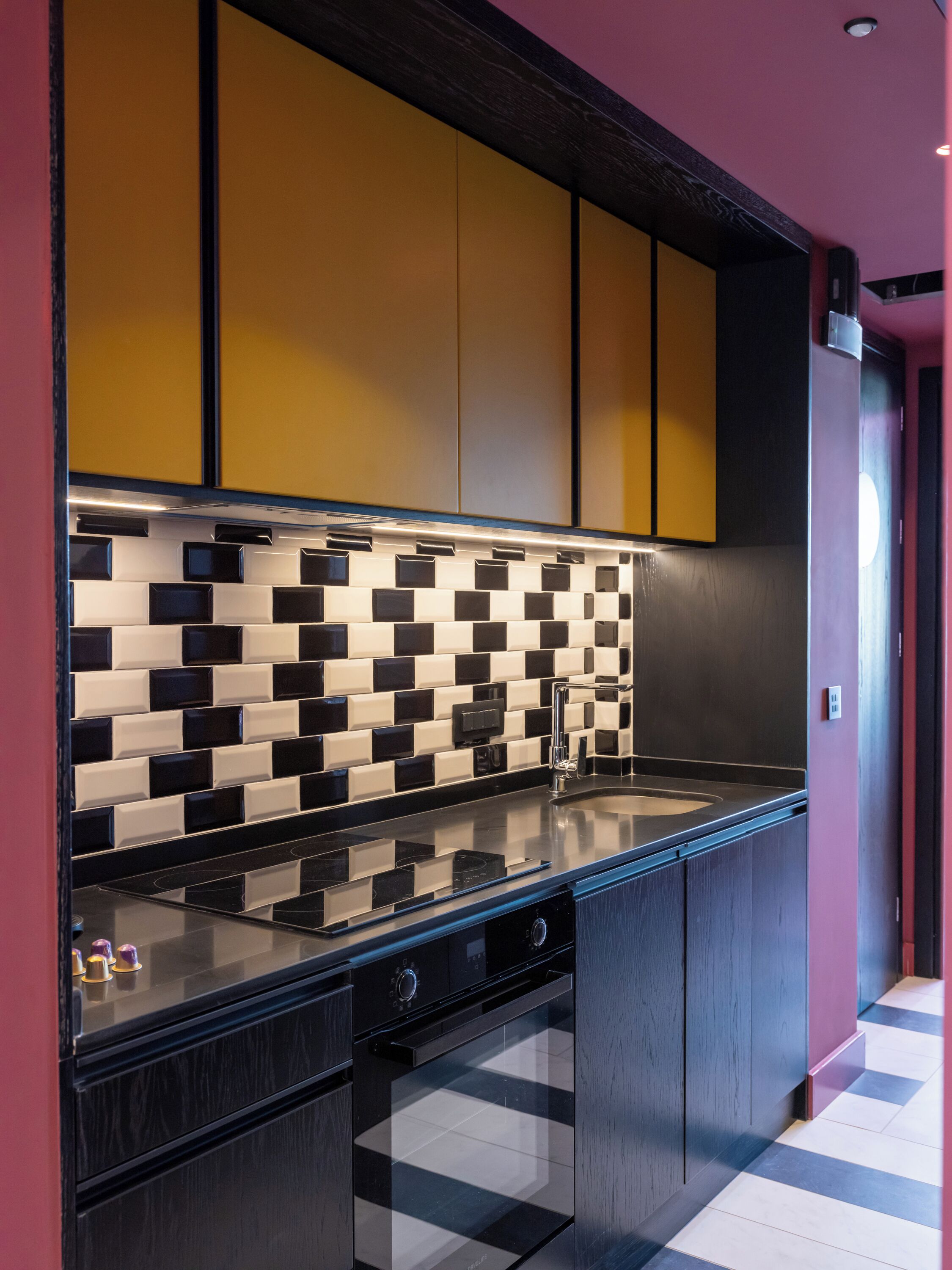 Una cocina moderna con salpicadero a cuadros blancos y negros, armarios oscuros y encimera de acero inoxidable.