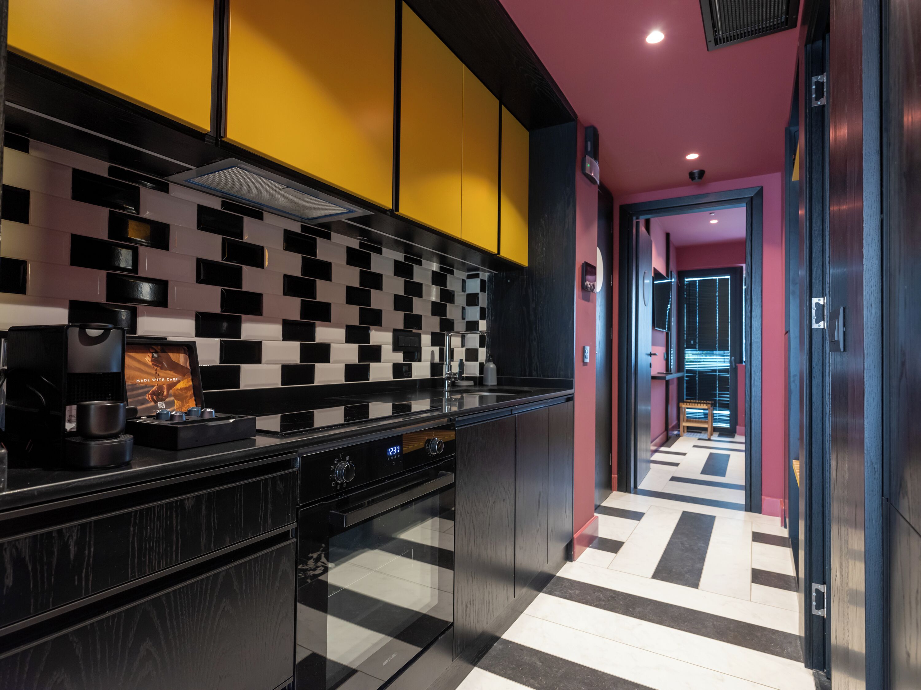 A modern kitchen with black and white checkered backsplash, a coffee machine, and a microwave.