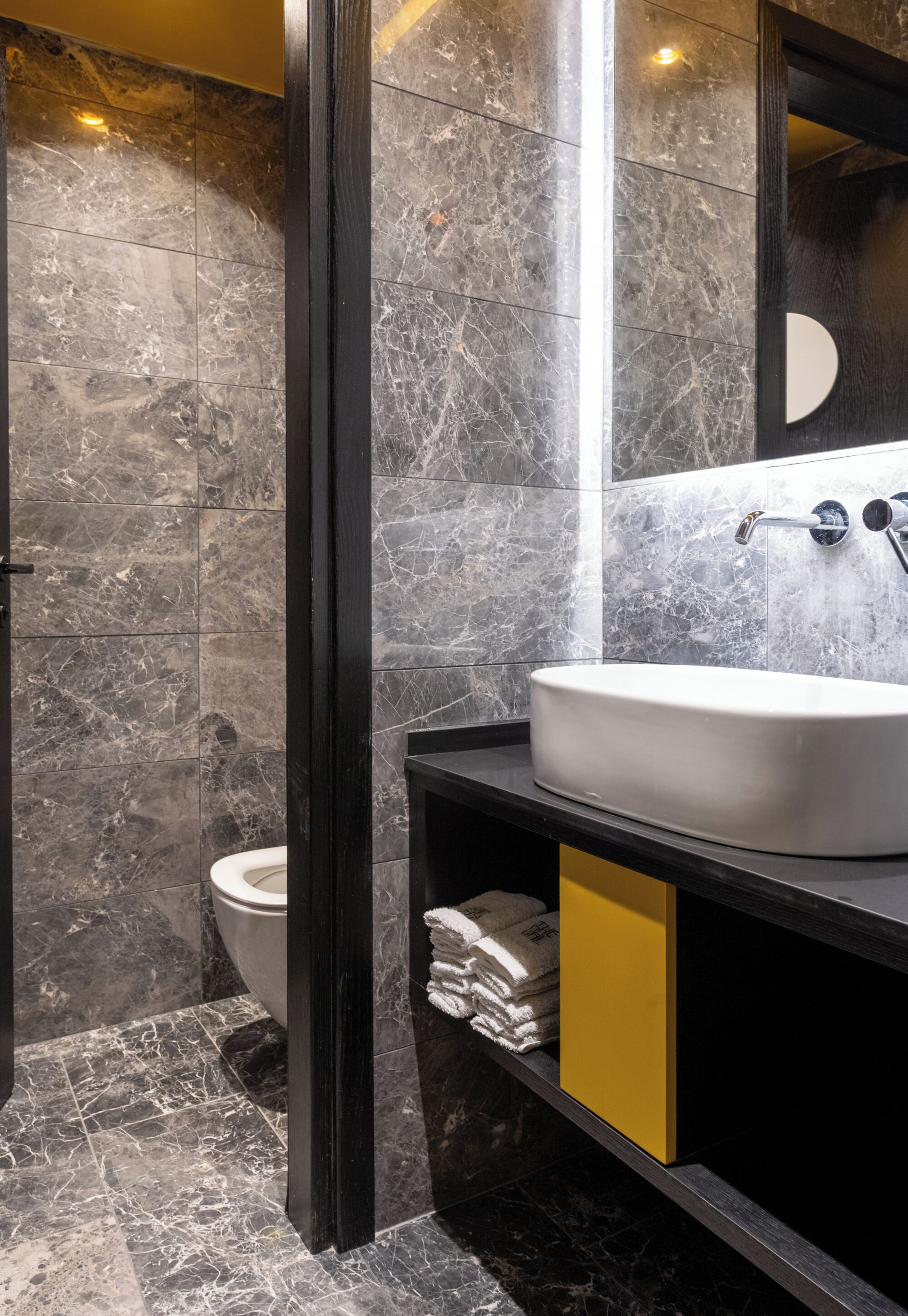 A bathroom with a marble floor, a white sink, and a toilet.