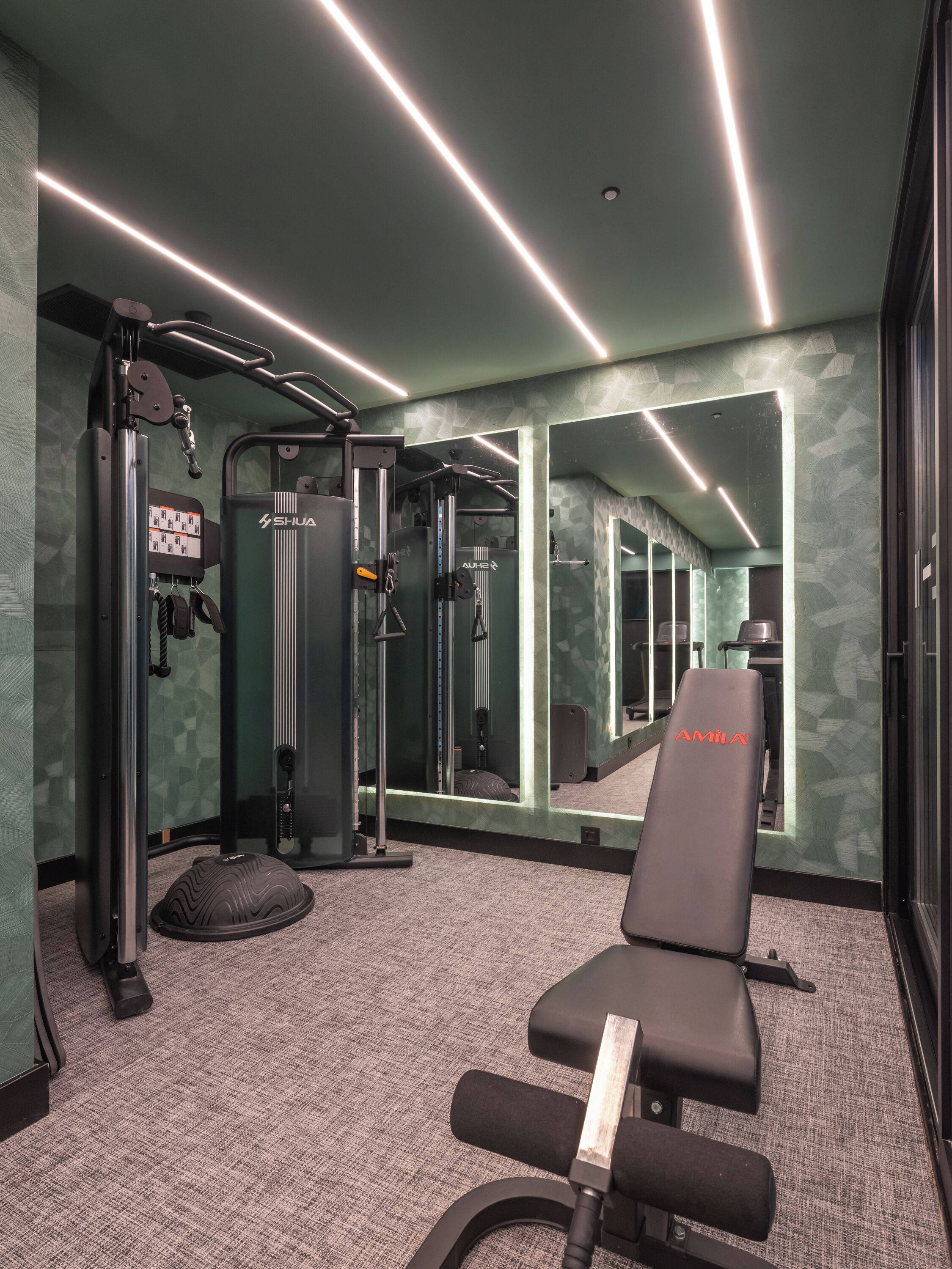 A gym with exercise equipment, a bench, and mirrors.