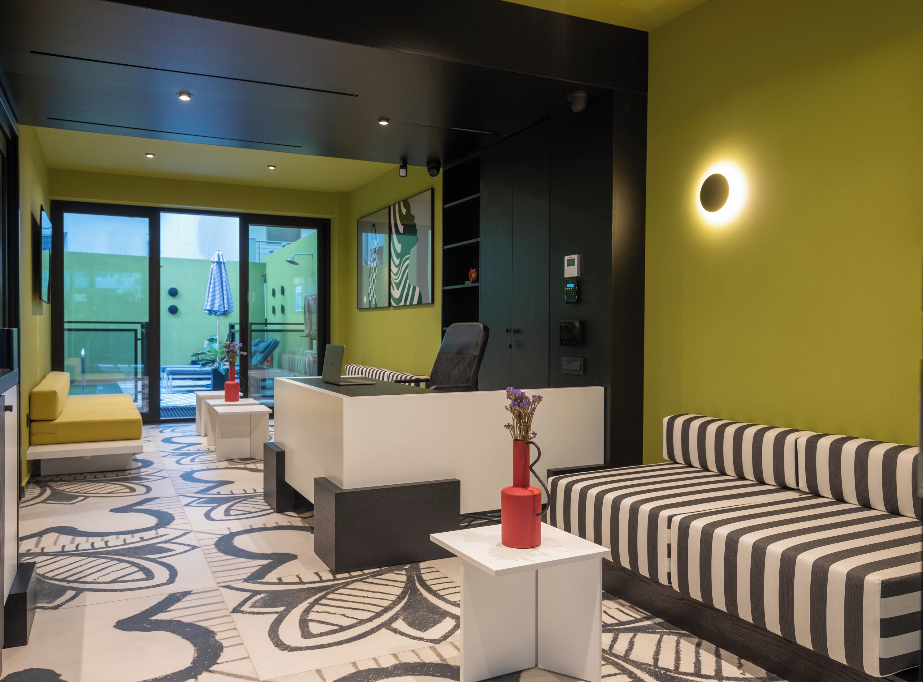 A modern interior with a reception desk, a striped sofa, and a patterned floor.