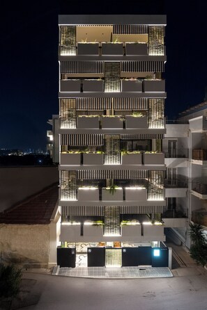 A multi-story building with balconies, a ground-level entrance, and a view of the cityscape in the background. - The Pal Living in a Concept (Heraklion)