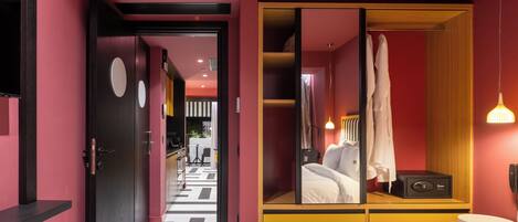 Een hotelkamer met een groot bed, een kledingkast met spiegel en een bureau met lamp.