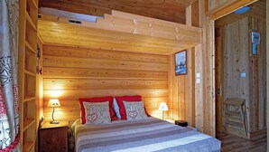 A wooden cabin bedroom with a bed, two bedside lamps, and a wooden ladder. - 6-person apartment (PASSY)
