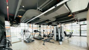 Une salle de sport moderne équipée de tapis de course, d’appareils de musculation et de divers équipements d’exercice.