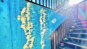 Una escalera con pared azul y barandilla de madera que conduce a un nivel superior.