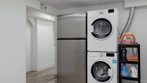 A compact kitchen with a stainless steel refrigerator and a built-in washer and dryer. - Cozy Basement suite Near UBC, Kits, and DT (Vancouver)