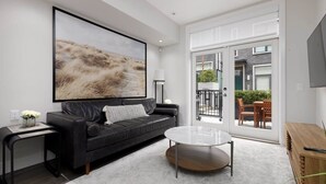 A modern living room with a black leather sofa, a white coffee table, and a large abstract painting on the wall.
