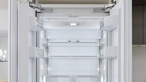 An open refrigerator with multiple shelves and a built-in ice maker.