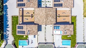 A rooftop pool area with multiple pools, solar panels, and outdoor seating areas.
