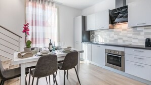 Una cocina moderna con armarios blancos, horno de acero inoxidable y salpicadero de azulejos.