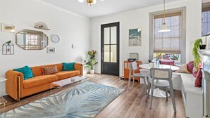 A modern living room with a sofa, coffee table, and a dining area with a table and chairs. - Old Spanish House Vivian Suite A. Sophisticated Retreat, Beach, Fire Pit, Downtown, Golf Cart (Biloxi)