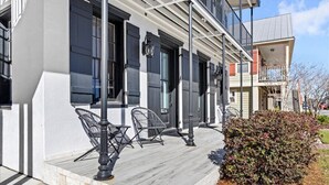 A building with a covered porch, outdoor seating, and a small garden area. - Old Spanish House Vivian Suite A. Sophisticated Retreat, Beach, Fire Pit, Downtown, Golf Cart (Biloxi)