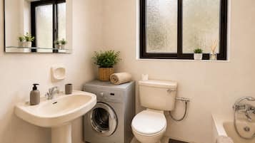Un bagno moderno con lavandino, lavatrice, wc e vasca da bagno.