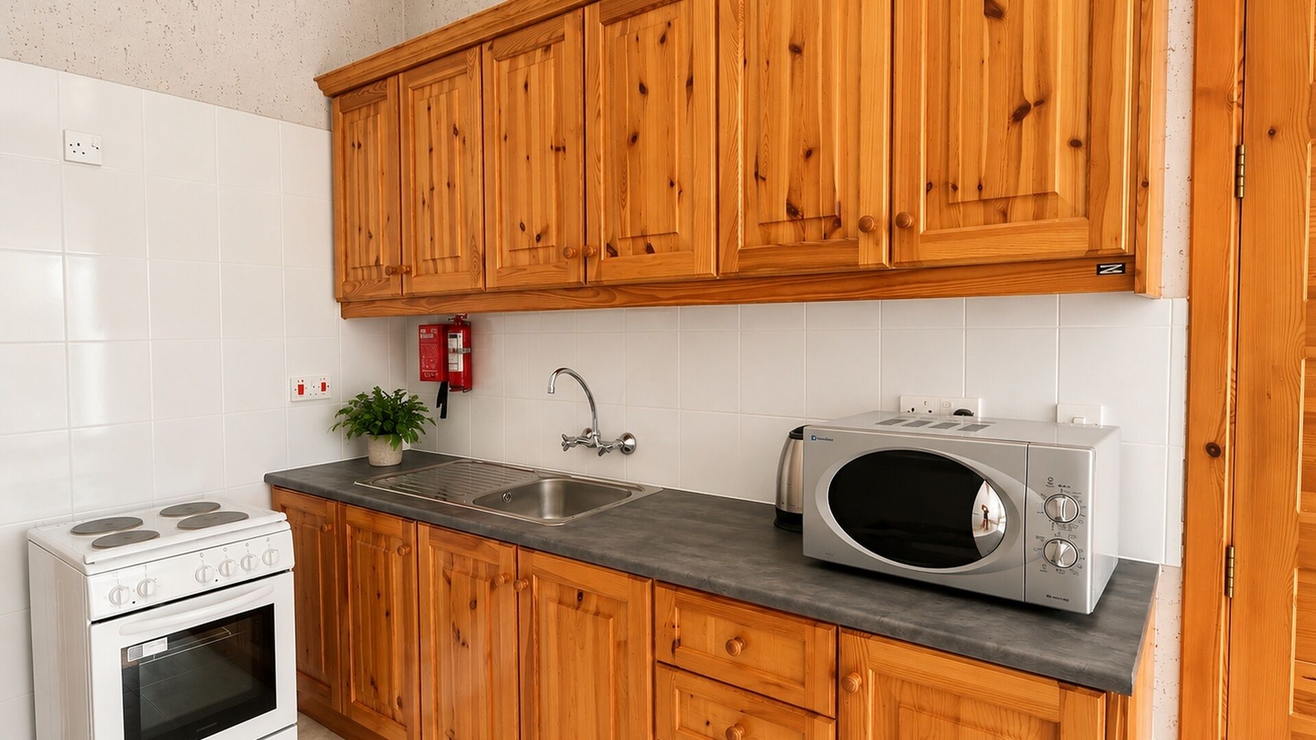 A kitchen with wooden cabinets, a stainless steel sink, a microwave, and a stove.