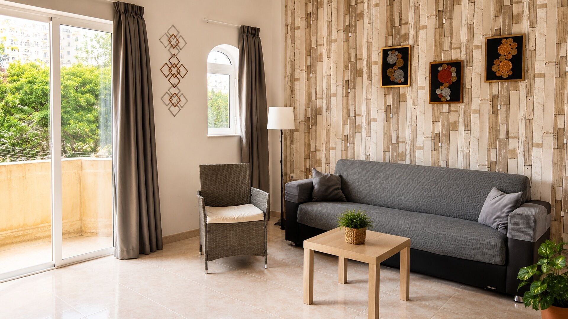 En stue med sofa, stol, bord og en potteplante.