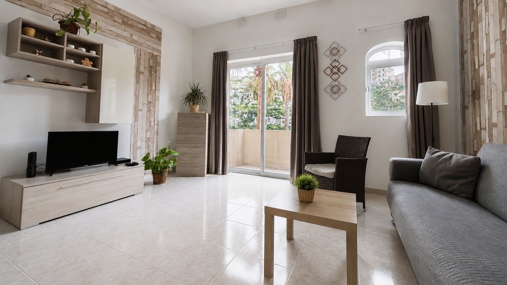 Een moderne woonkamer met een flatscreen-televisie, een bank, een salontafel en een balkon met gordijnen.